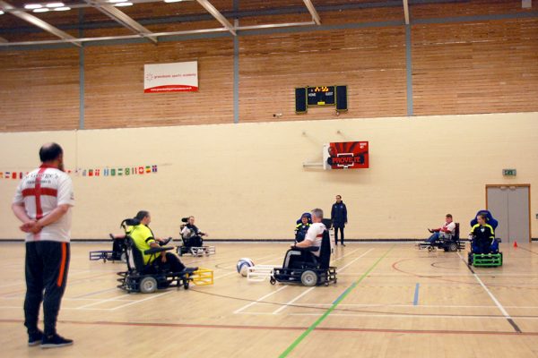 people playing wheelchair football in a sports hall