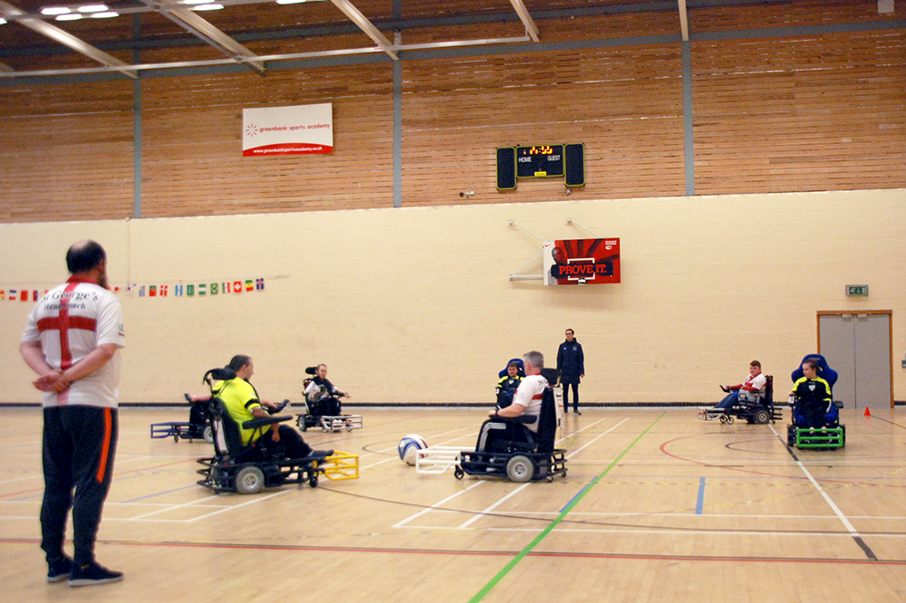 people playing wheelchair football in a sports hall